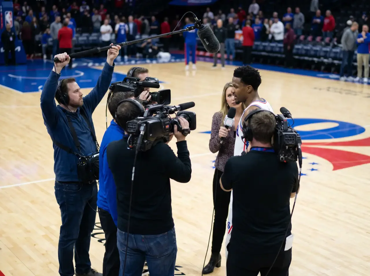 Basketball player interviewed by media on the court after a game in Philadelphia